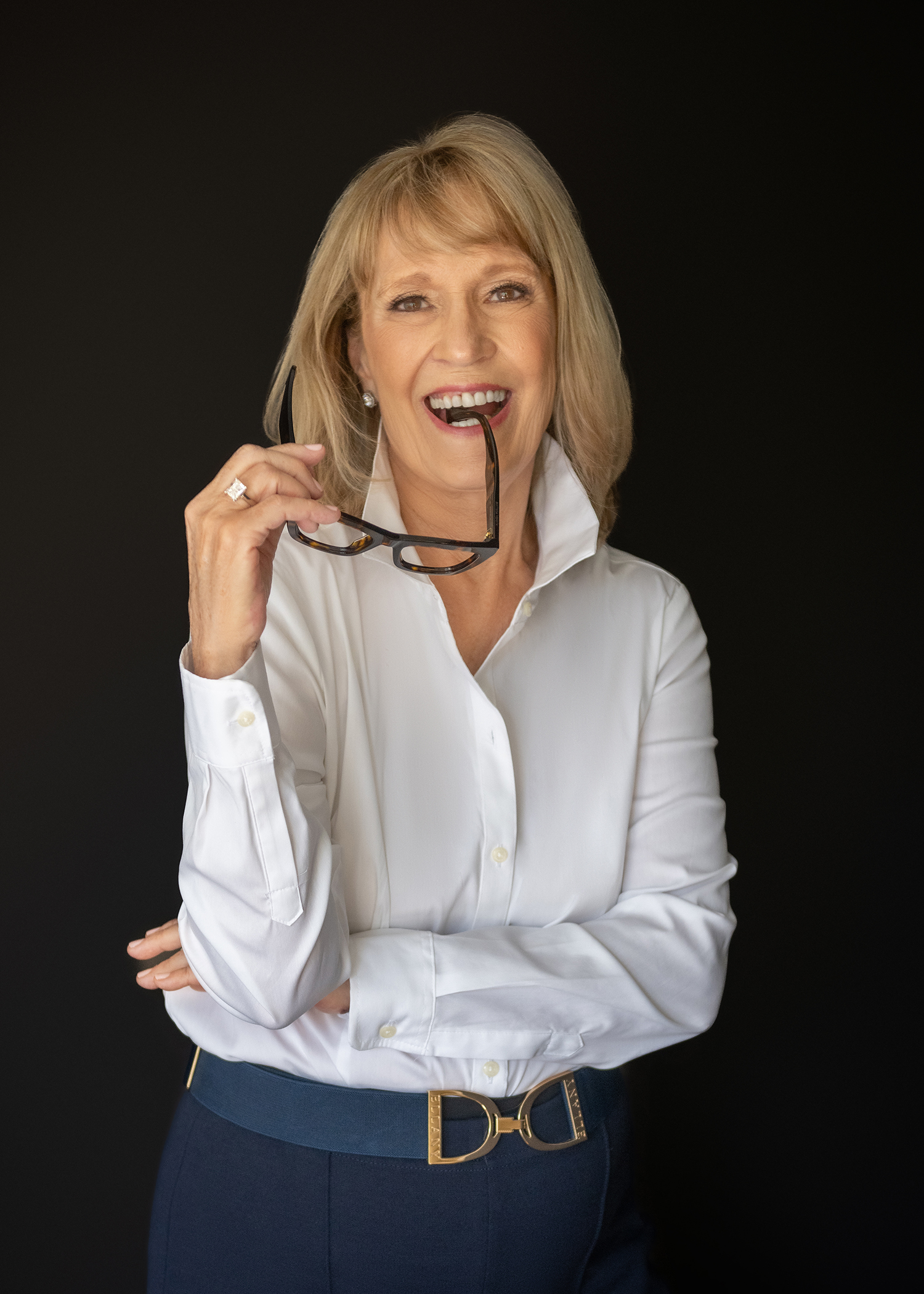 Man in blue blazer and woman in white blouse laughing together in a professional studio portrait session